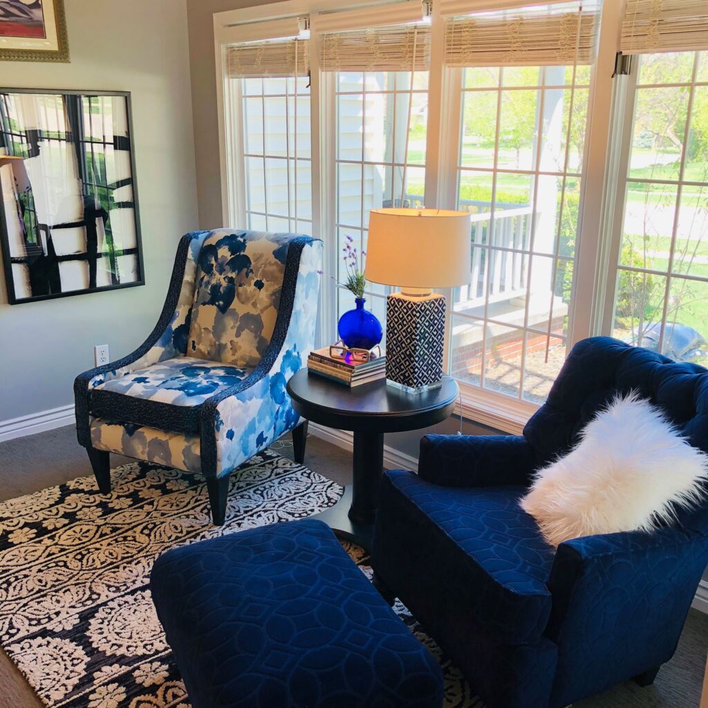 Two upholstered chairs in front of windows.