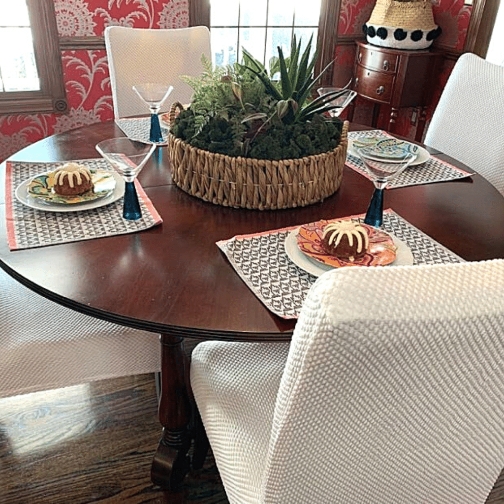 A plant garden in a woven basket on a dining room table.