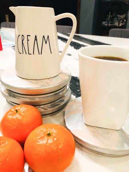 A cream pitcher sitting on a stack of DIY decoupage coasters.