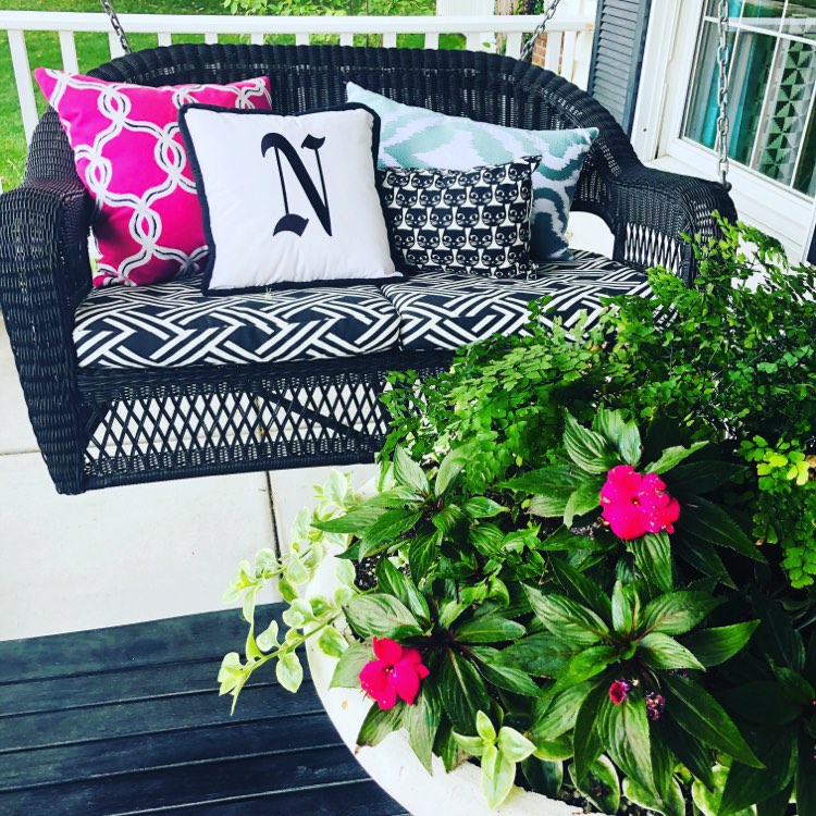 A porch swing decorated for spring and summer.