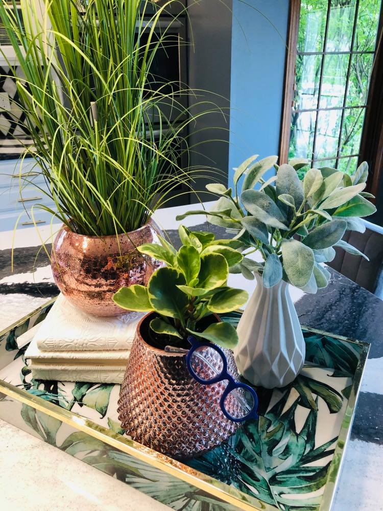 Three small vases and some books on a tray is a kitchen island decor idea.