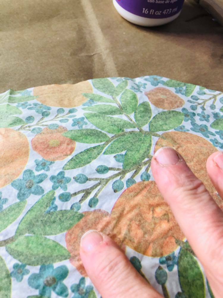 Smoothing the tissue paper onto the plate with fingers.