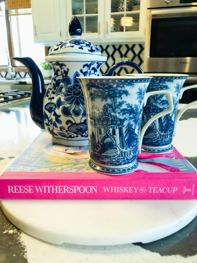 A teapot and two cups sitting on top of a colorful home decor book.