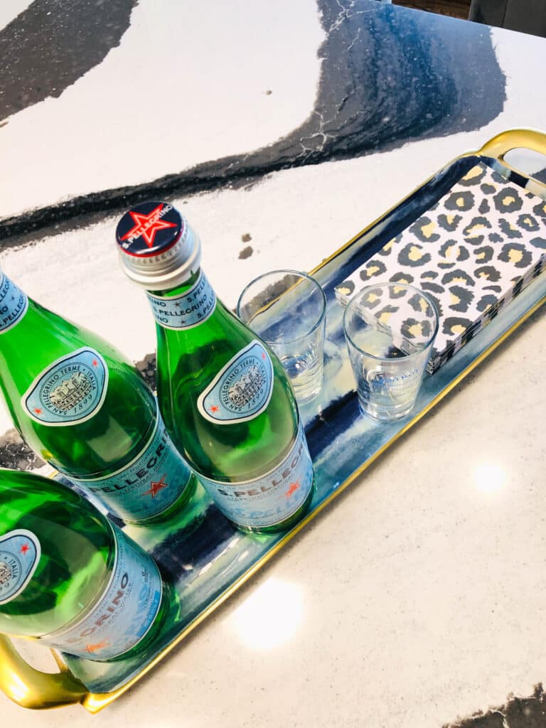 A narrow try with sparkling water bottles and glasses are a decorative mini bar for your kitchen island.