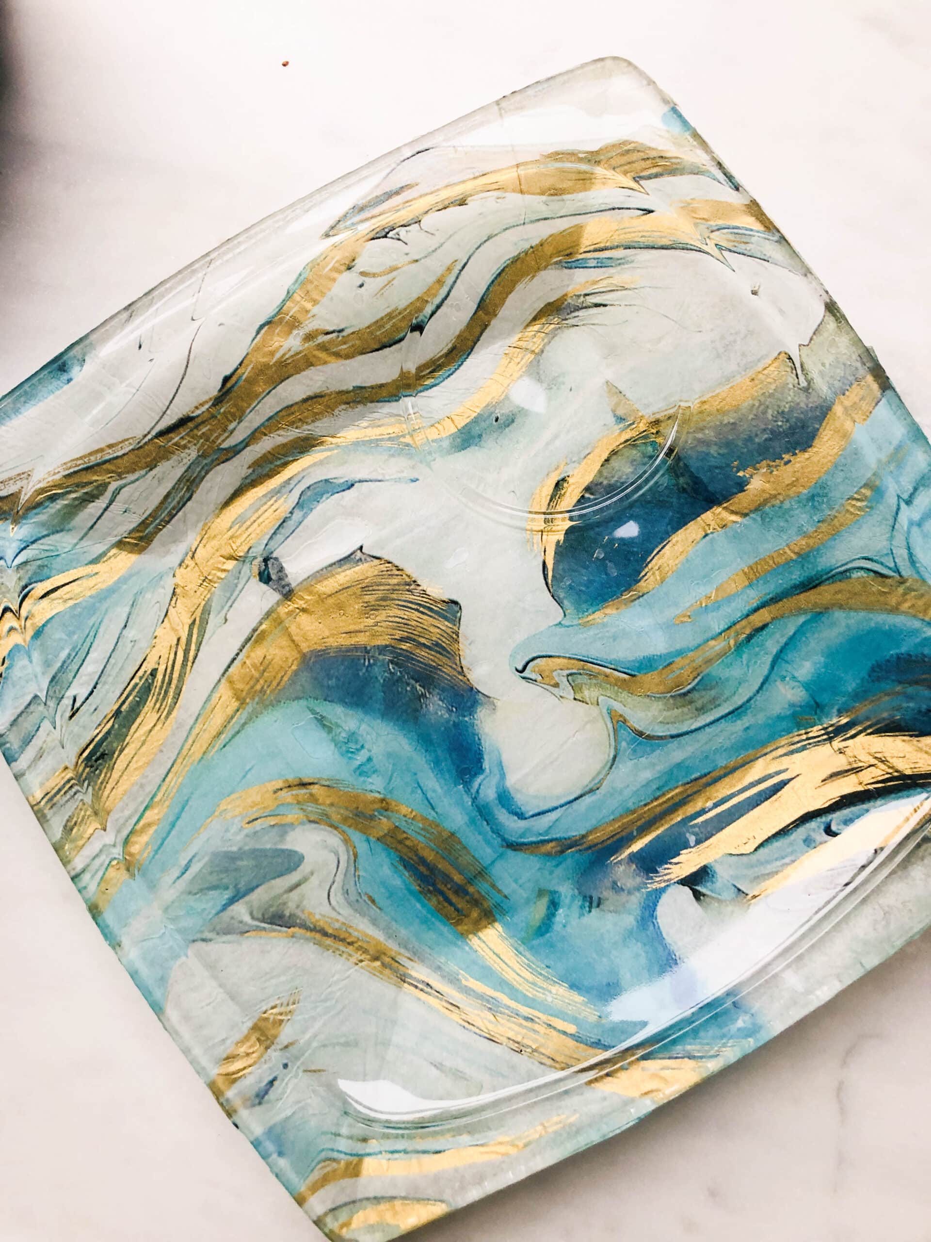 A square decoupage glass platte with gold and blue tissue paper.