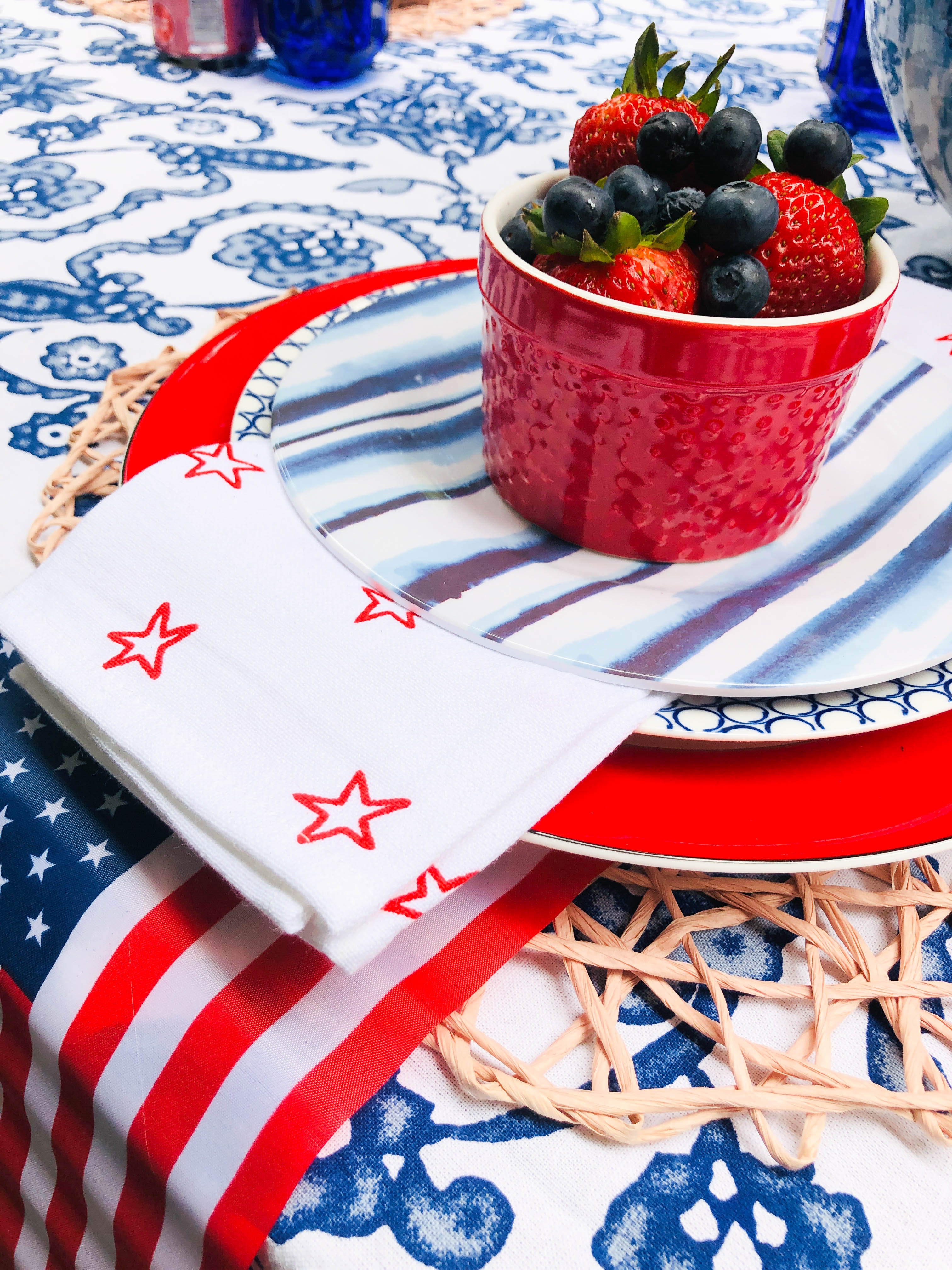 The 4th of July table  setting with three stacked plates on top of a woven placemat used as decorations.