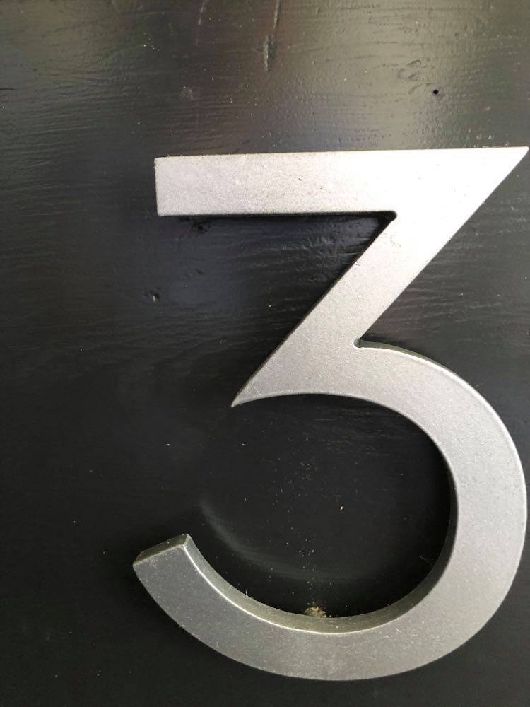 A number 3 house number that is attached to a wood file drawer as part of this diy file cabinet makeover project.
