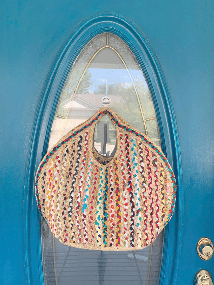 A woven handbag hanging from a hook on the front door.