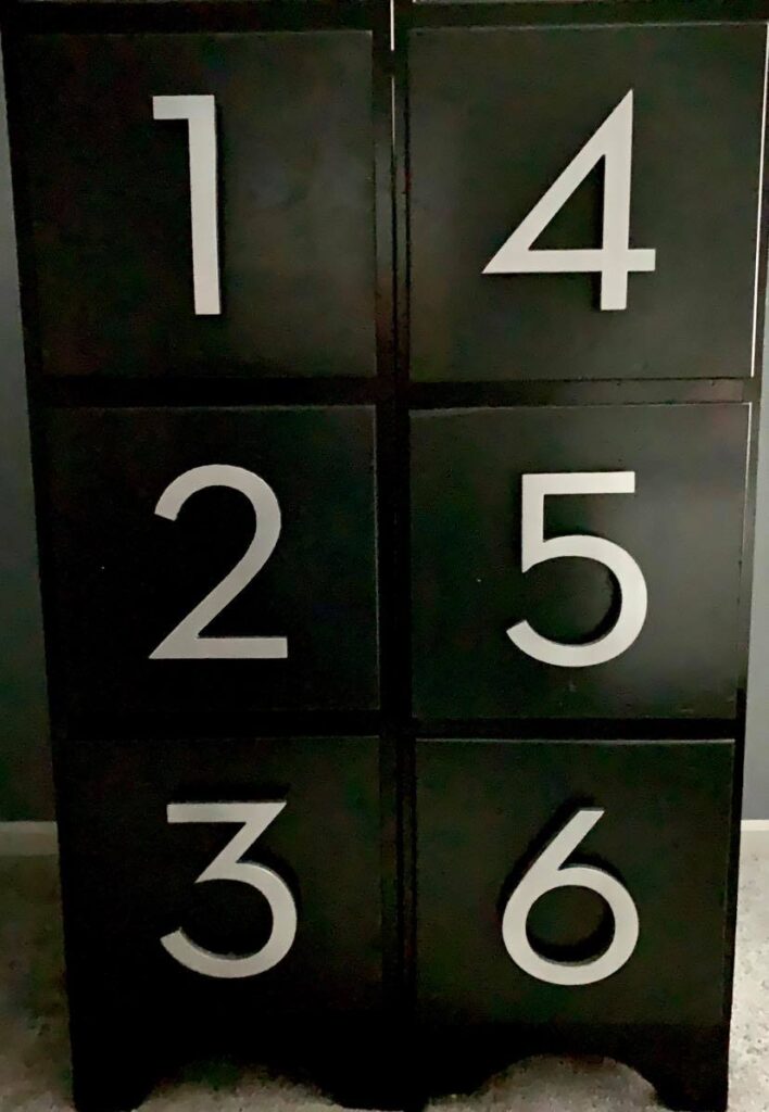 Six different house numbers attached to the six drawer of the file cabinets.