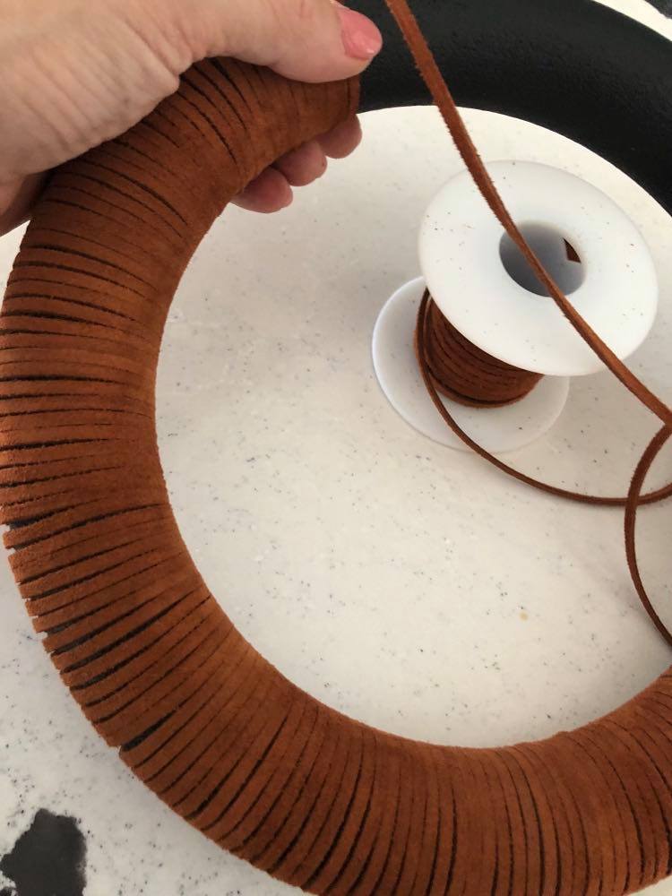Covering a wreath form with suede lacing.