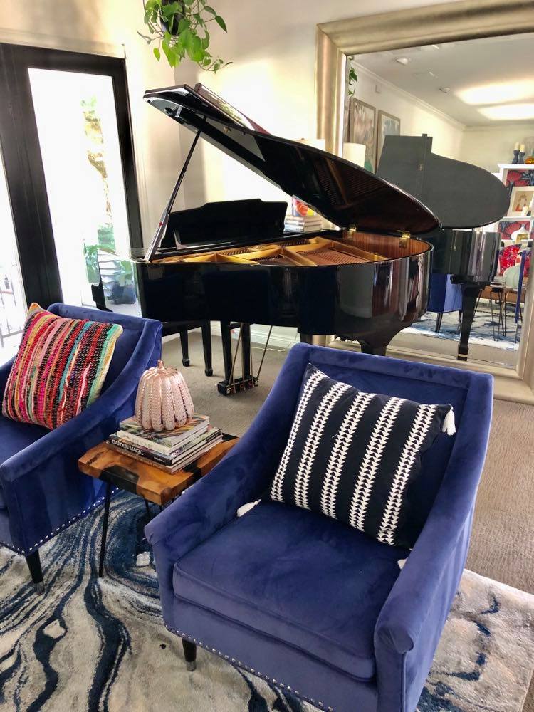 The piano reflected in a large mirror makes the living room appear larger.