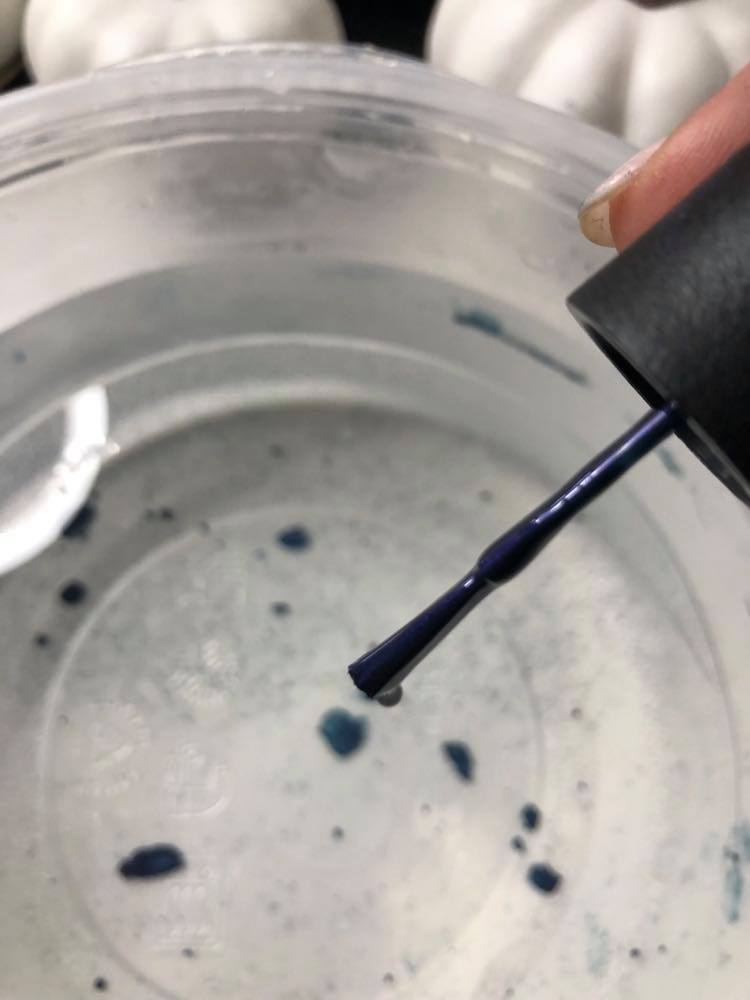 Dropping nail polish into a bowl of water.