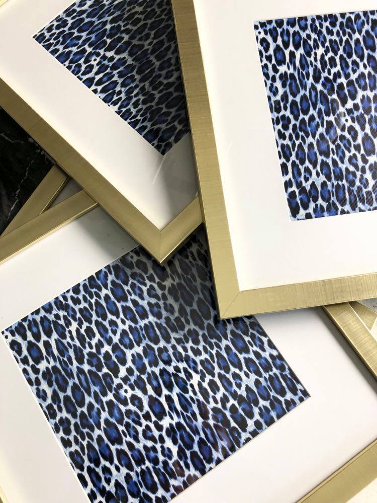 Blue cheetah wrapping paper inserted into gold frames for the ultimate wall art hack.