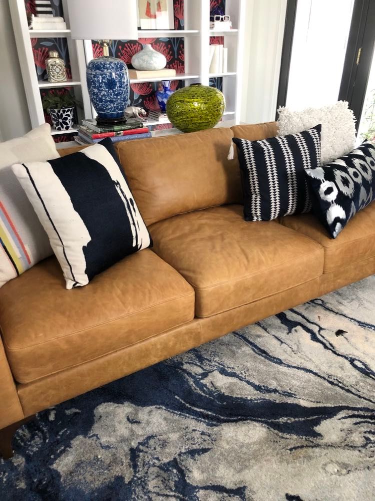 A neutral color palette is used to style the pillows on this sofa.