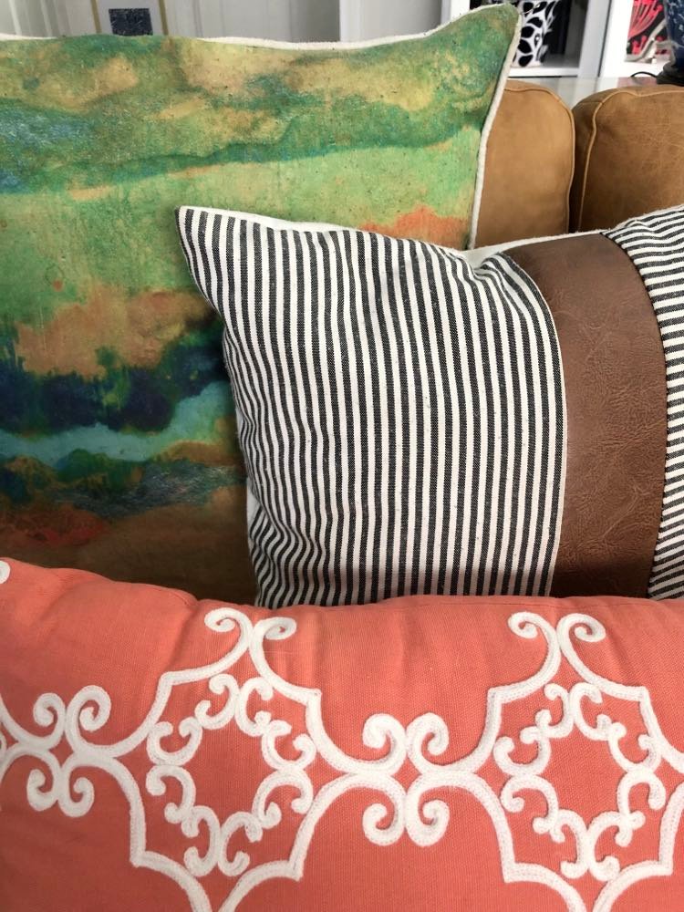 Close up of brightly colored pillows in oranges, blues, and browns.