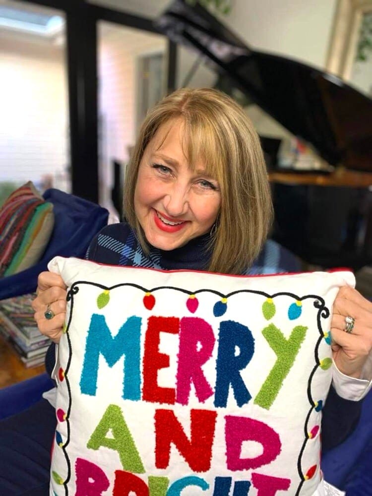 Missy holding a pillow that says "Merry and Bright."