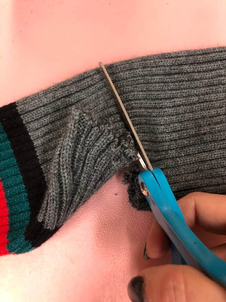 Cutting the sleeve from the sweater.