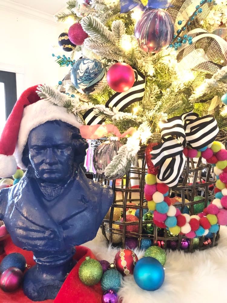 A bust of Beethoven sitting beside the Merry and Bright Christmas tree.