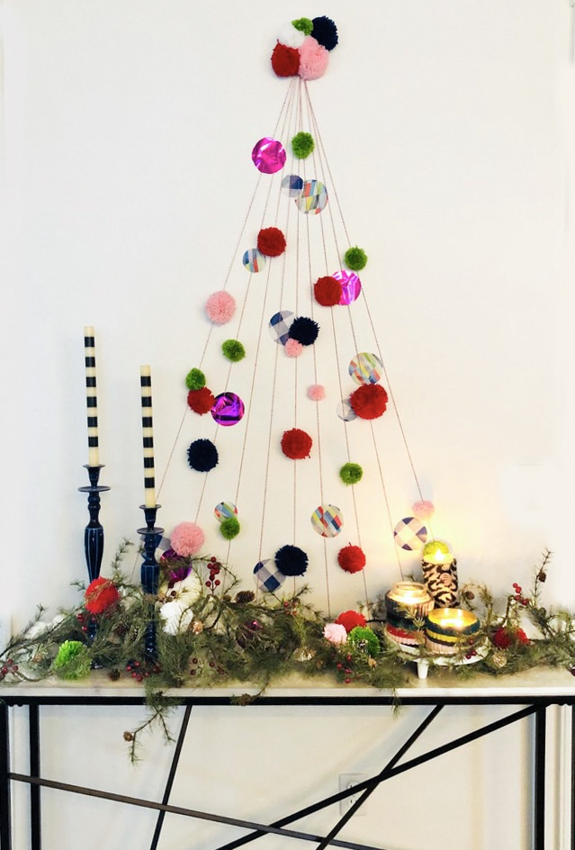 A decorated DIY wall Christmas tree that sits above a console table.