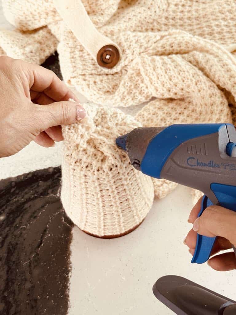 Hot gluing the cut edge to the bottom of the jar candle.