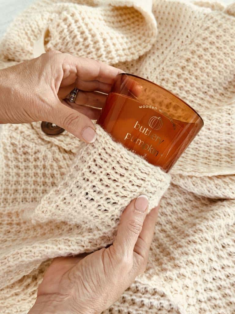 Sliding a sweater sleeve ovr the bottom of a jar candle.