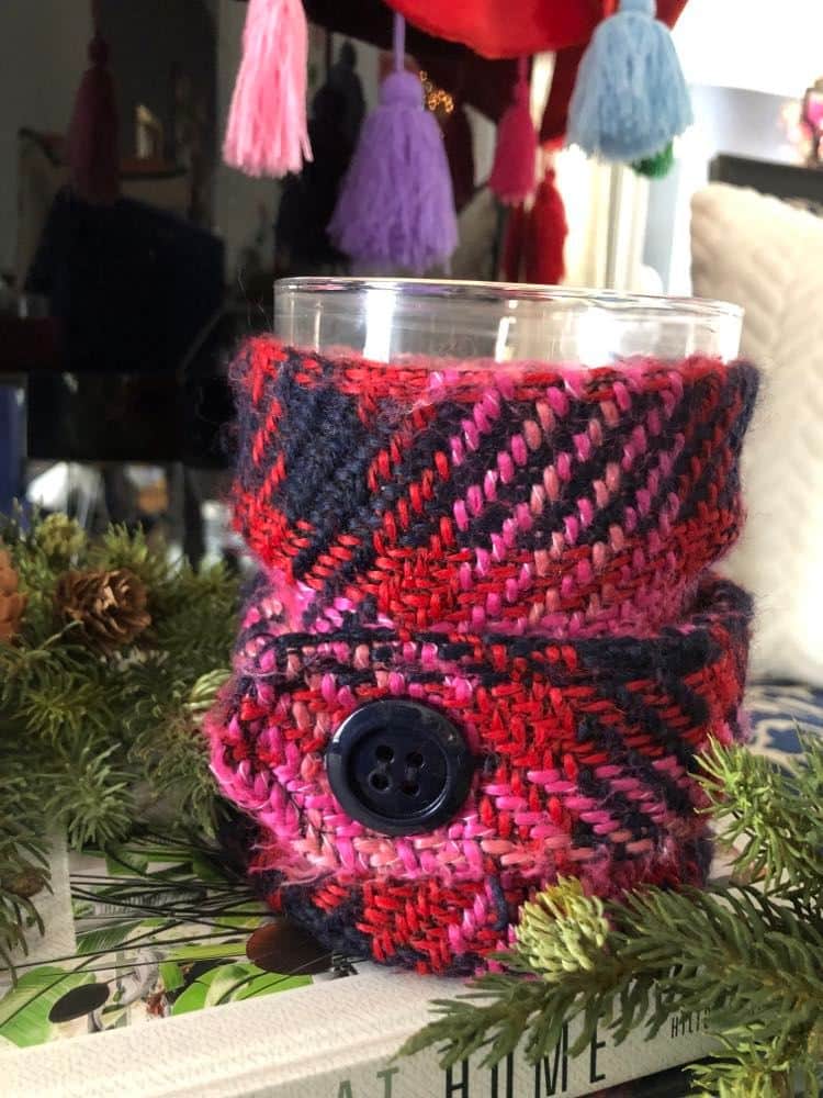 A pink plaid sleeve on a Christmas jar candle.