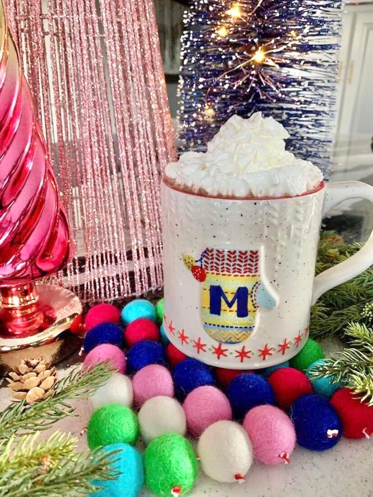 A mug of hot chocolate sitting on a felted wool ball trivet.