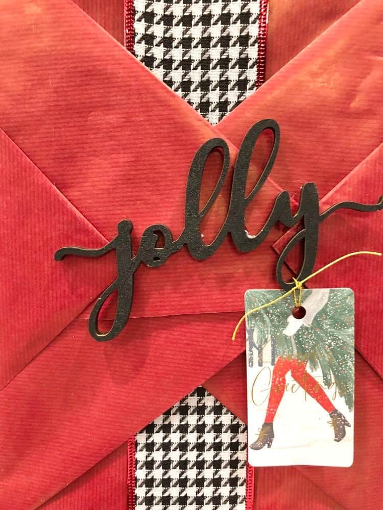 Red wrapping paper on a gift with a wood word "jolly"