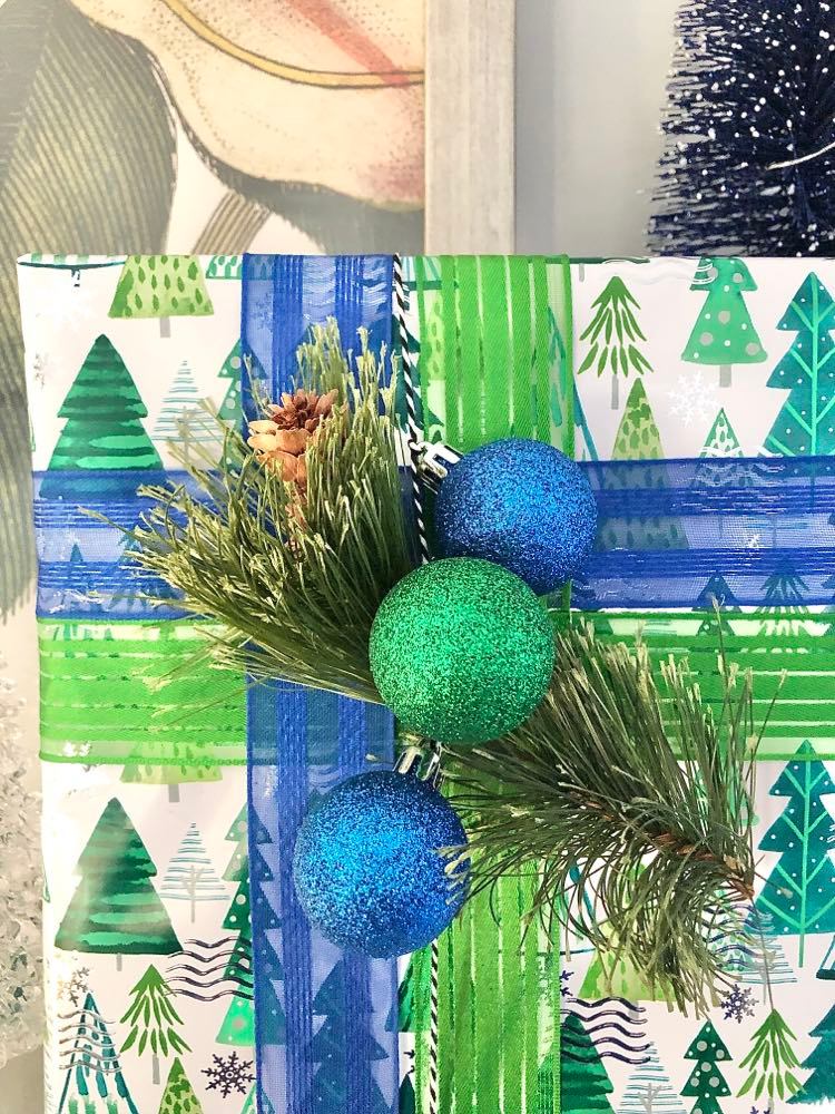 Green and blue ornament balls attached to a Christmas gift.
