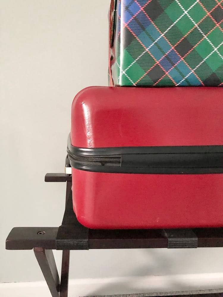 A suitcase and wrapped gift sitting on top of a suitcase rack.