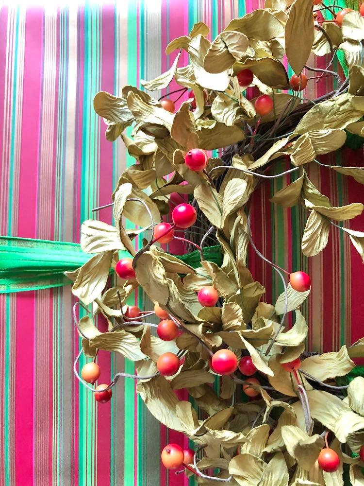 A winterberry wreath tied to a large Christmas package.
