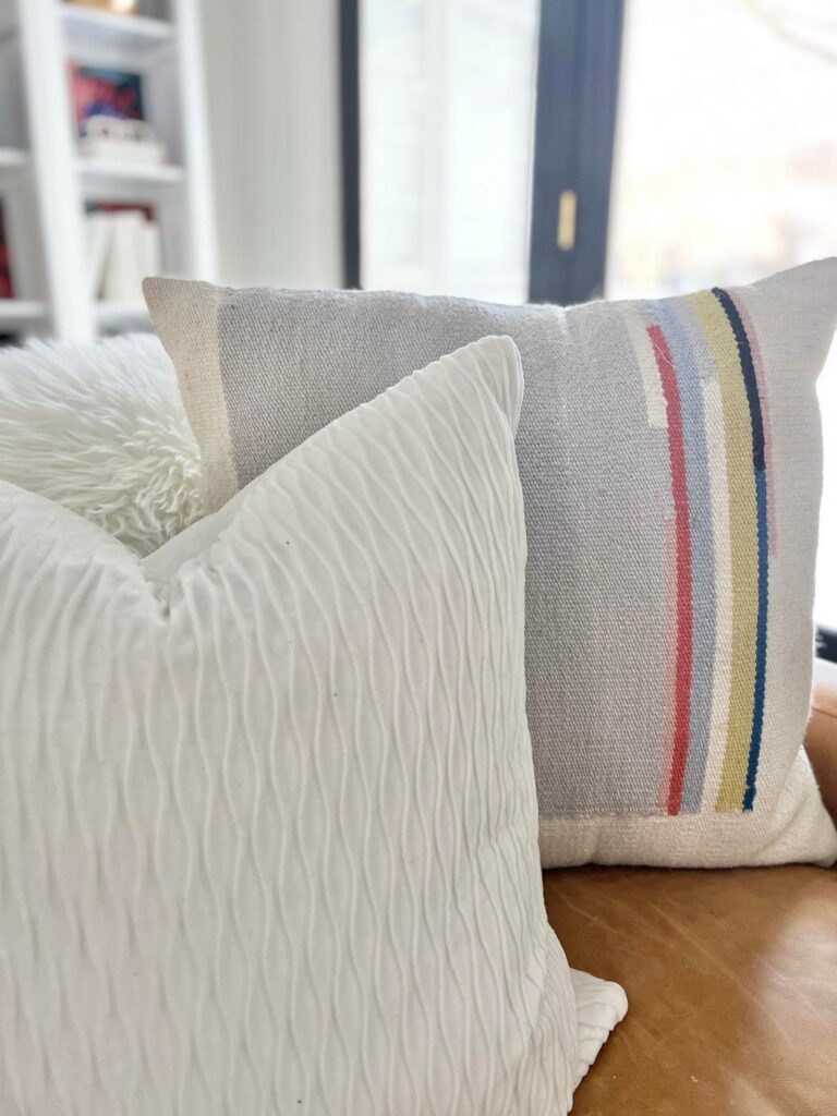 Two white pillows sitting on a brown leather sofa.