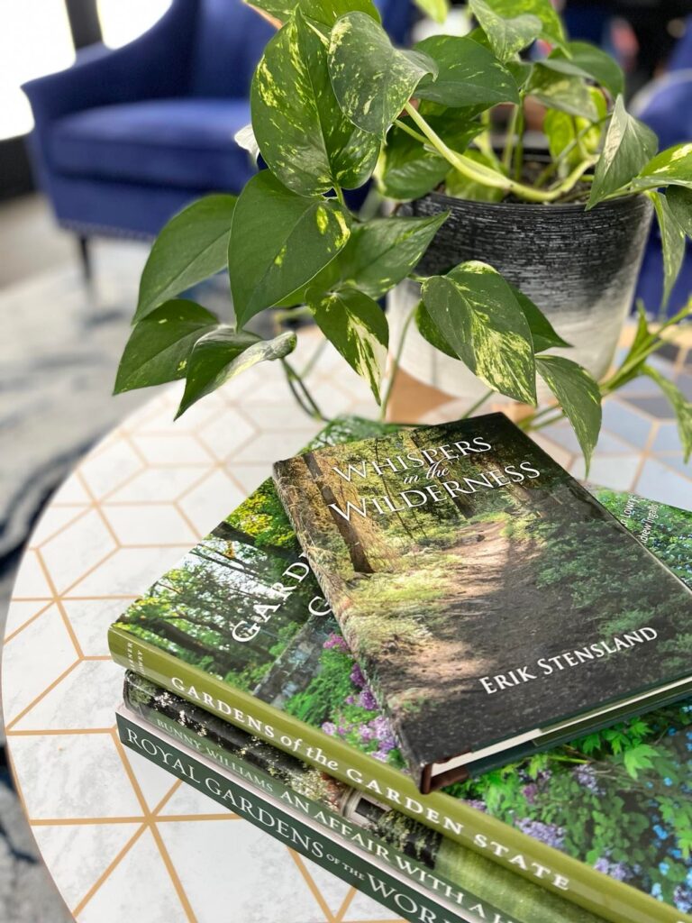 A stack of gardening books sitting on a coffee table.  