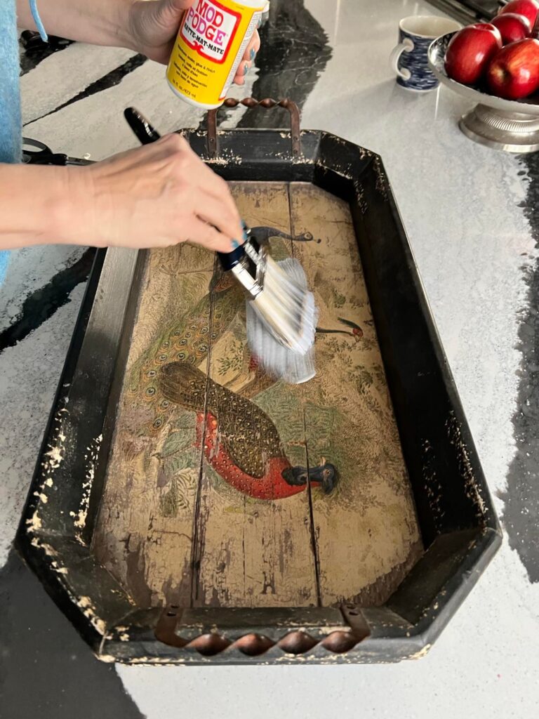 Brushing Mod Podge on a wood tray.