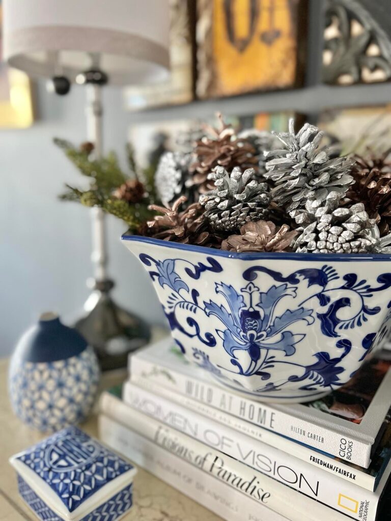 Blue and white bowl full of greenery and painted pine cones to transition from Christmas to winter decor.