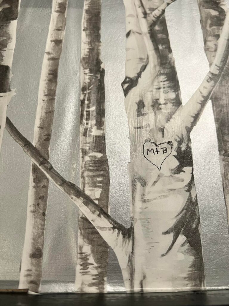 A close up of the wallpaper with the initial M + B written on a tree branch.