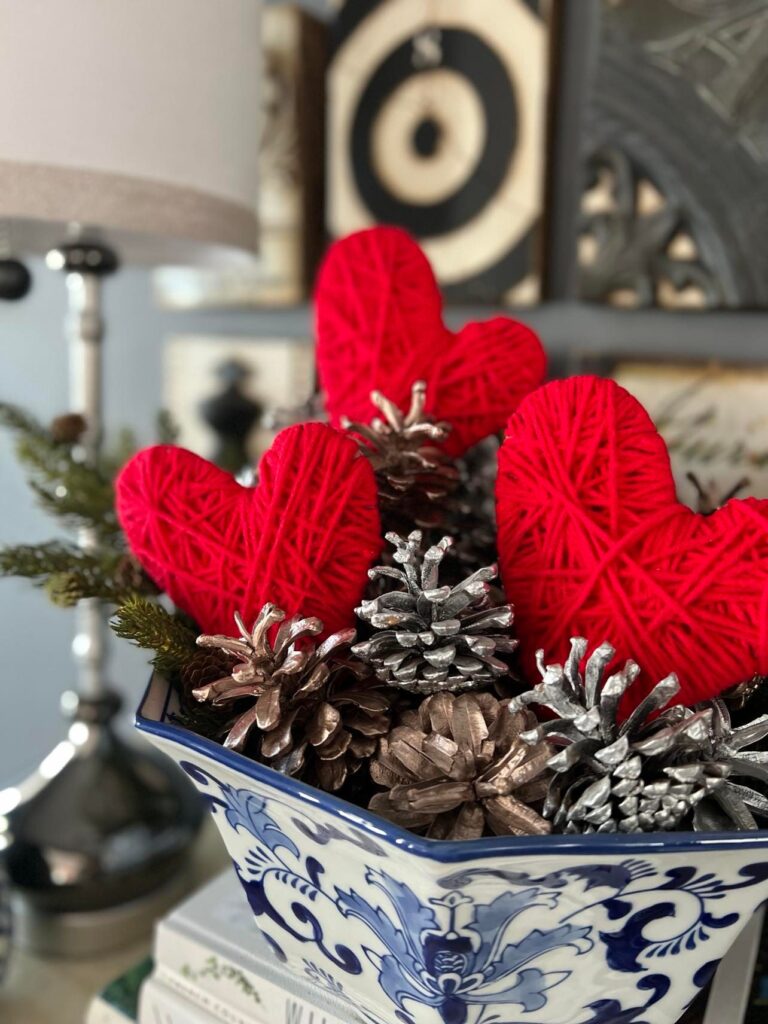 Easy Valentine's Day home decor is yarn wrapped cardboard hearts placed in a blue and white bowl.