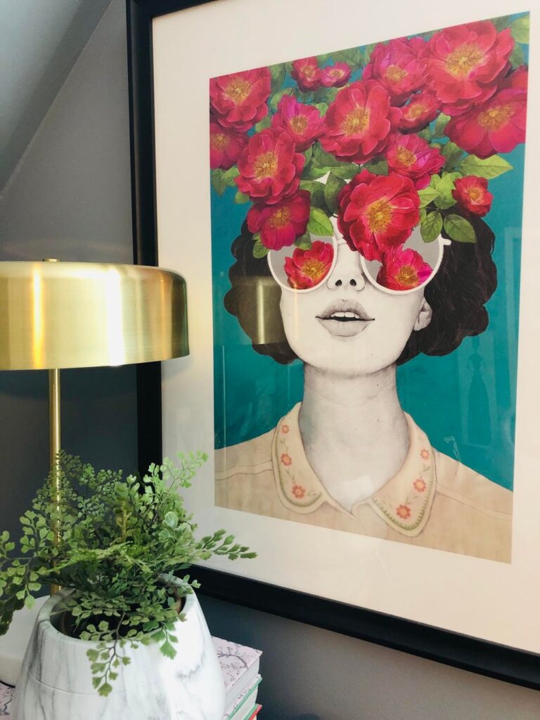 Wall art depicting a woman with red flowers spilling from her glasses.