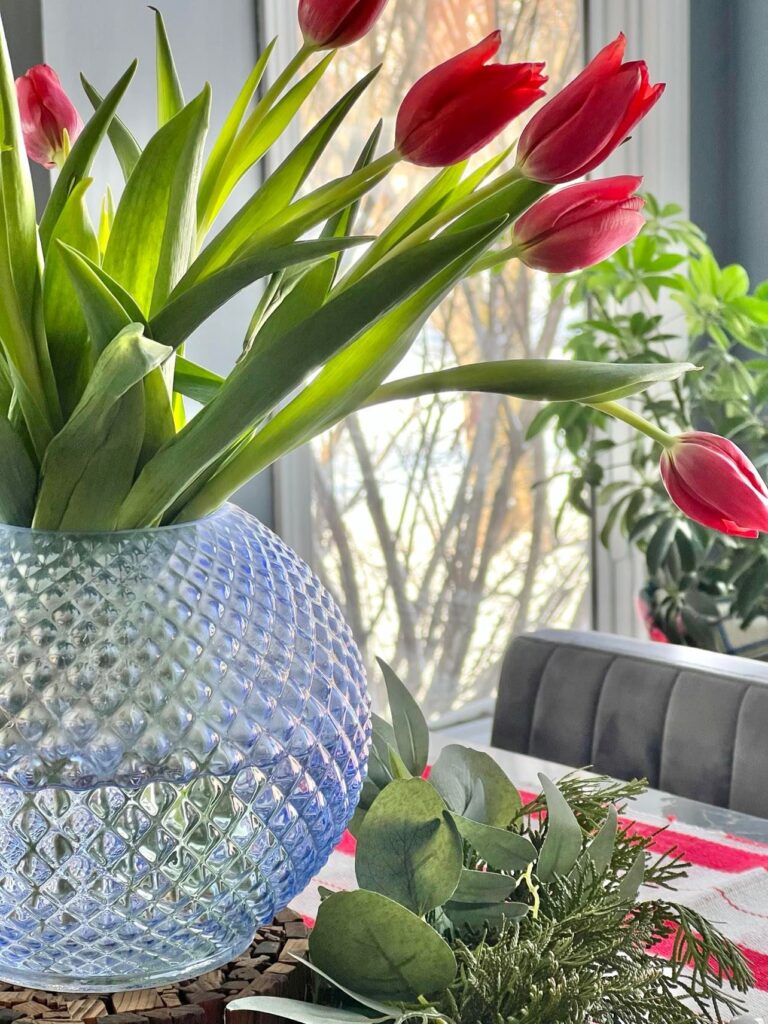 Fresh red tulips in a blue glass vase.