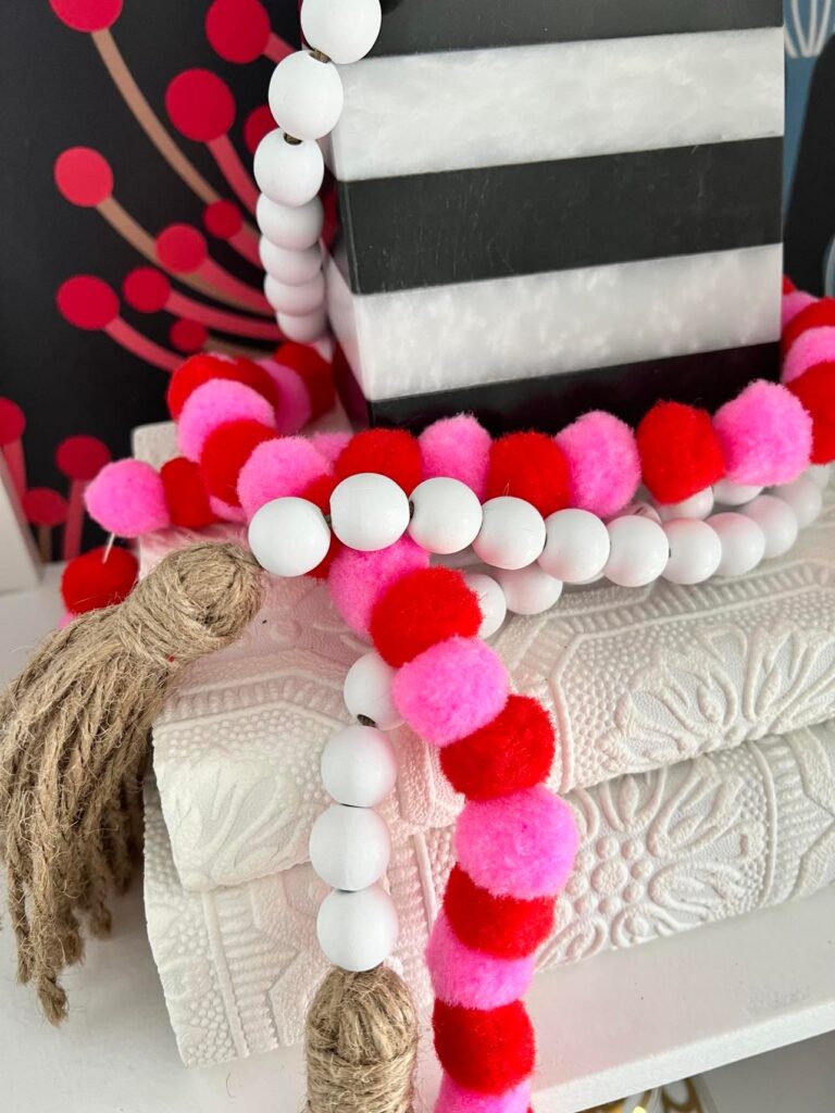 Decorate for Valentine's Day with a pom-pom garland displayed on books.