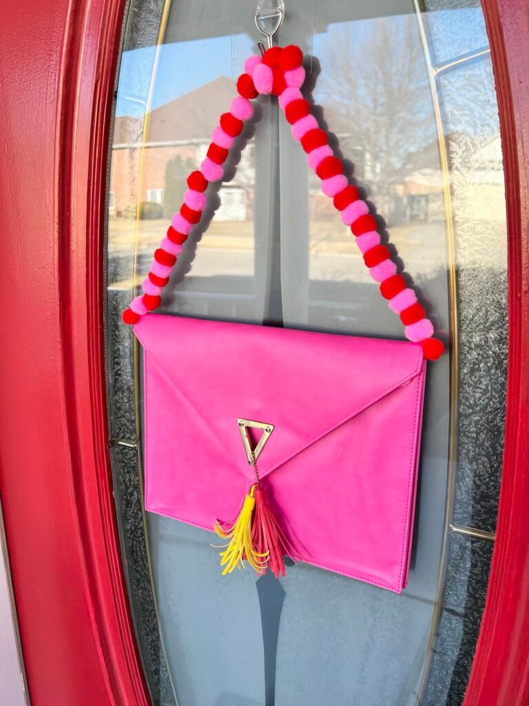 An idea for Valentine's Day Home Decor is a hanging purse pouch on the front door.