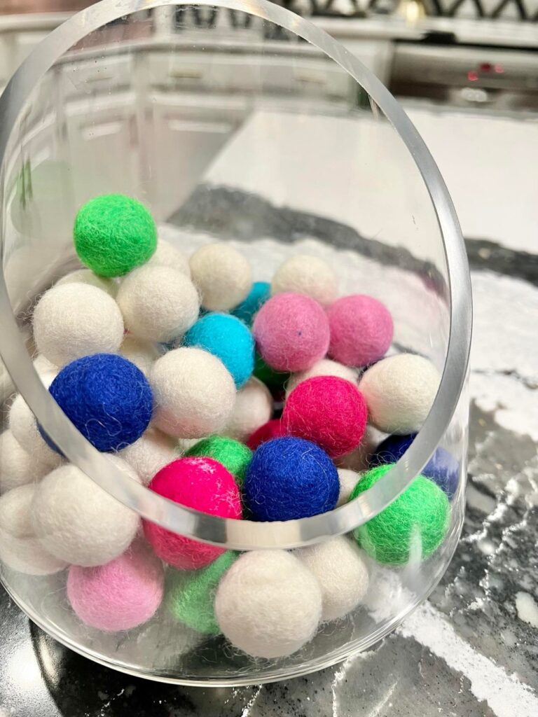 Glass jar filled with wool felt balls of various colors.