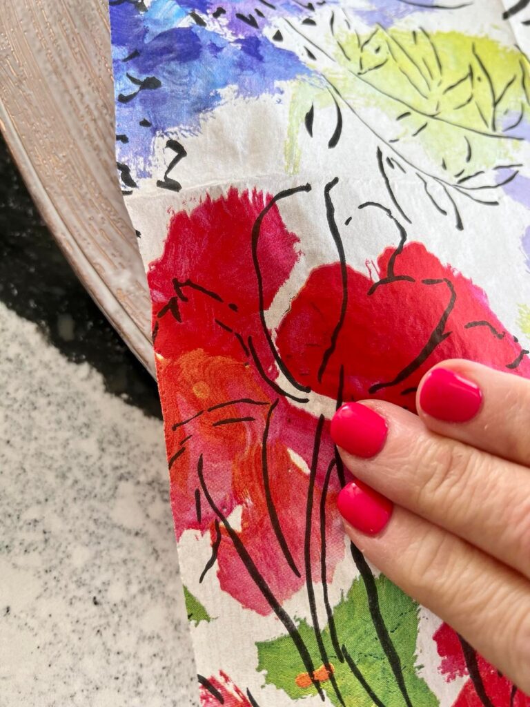 Fingers pressing the paper napkin on to the decoupage glue.