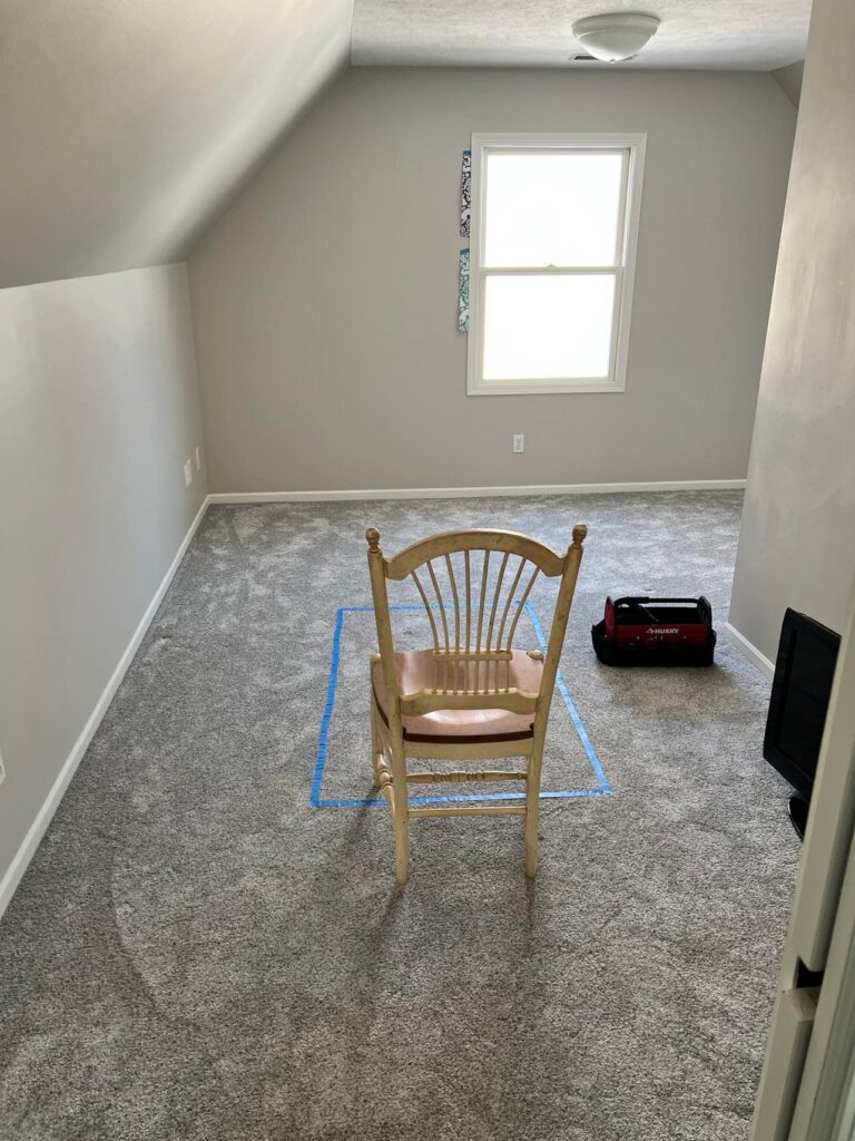 An empty room with a lone chair sitting in the middle. The new craft room space.