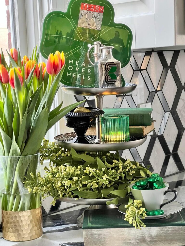 Add a wee bit o'green decor with this three tired tray that is holding a green candles, green books, a green shamrock record album and flanked by some red and yellow tuips.