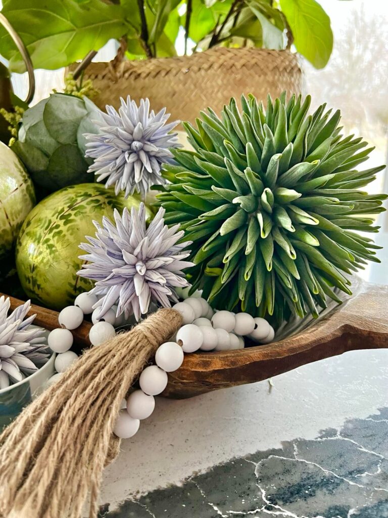 A dough bowl display with beads and round decorative balls.