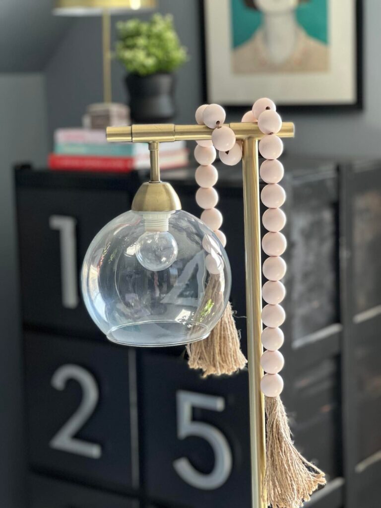 A bead garland draped on a desk lamp.