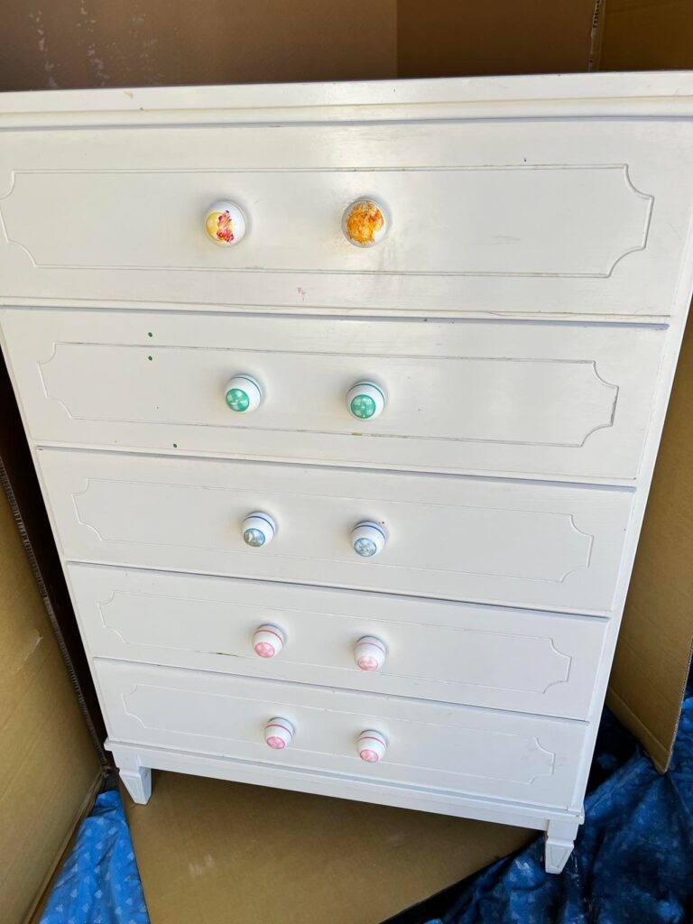 A beaten up white dresser.