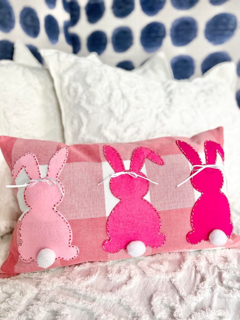 The completed DIY bunny pillow with three stitched bunnies in different shades of pink.
