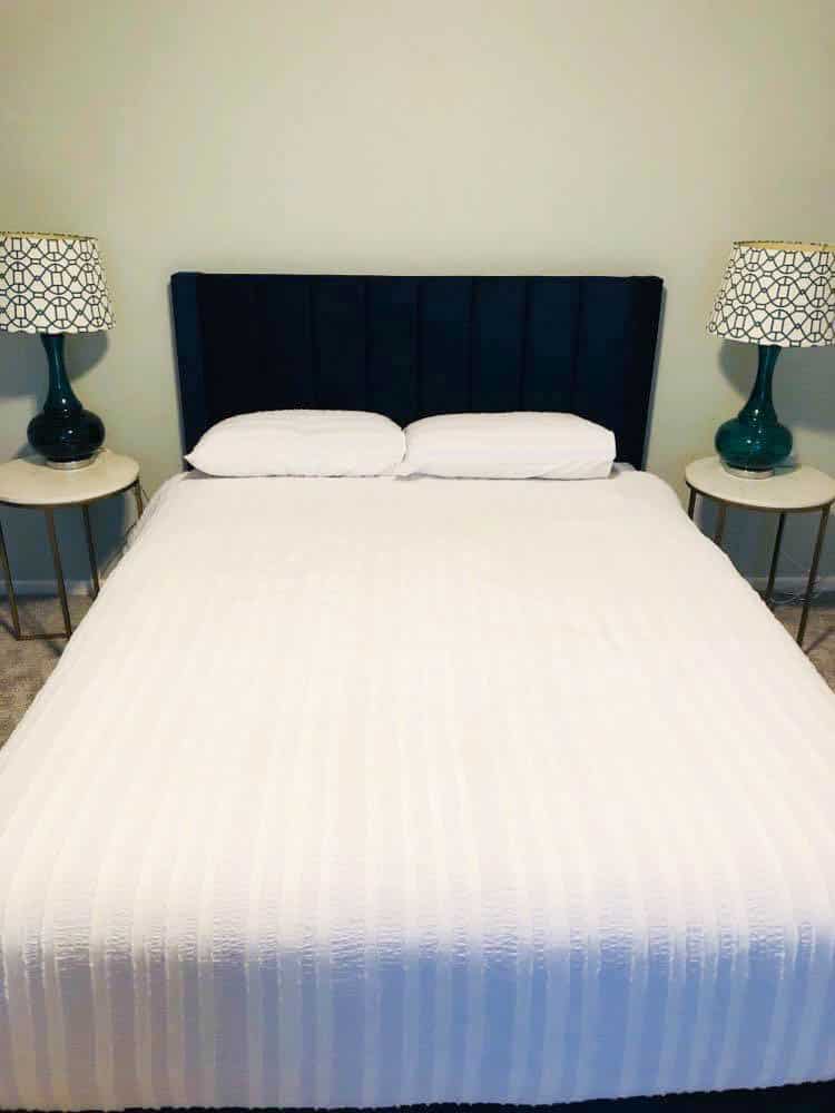 The guest bedroom queen size bed with navy blue headboard.